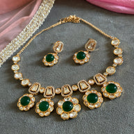 Ornate gold necklace with pearl and gemstone details on a gray surface.
