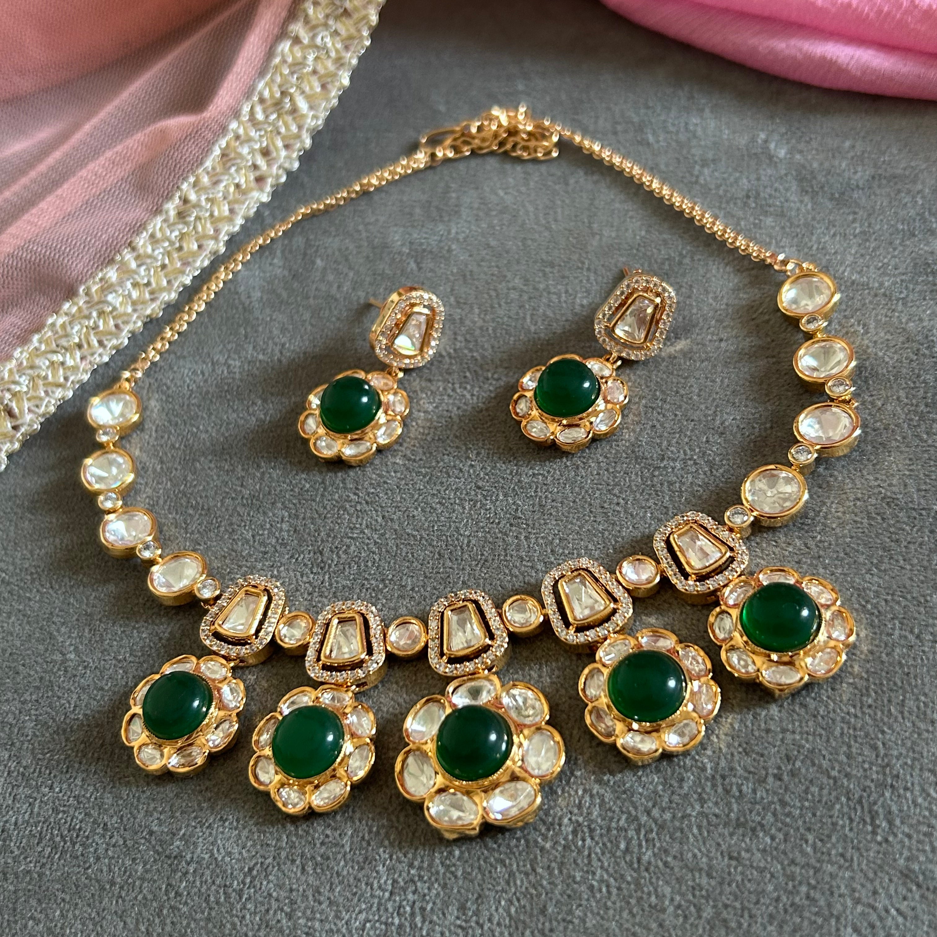 Ornate gold necklace with pearl and gemstone details on a gray surface.