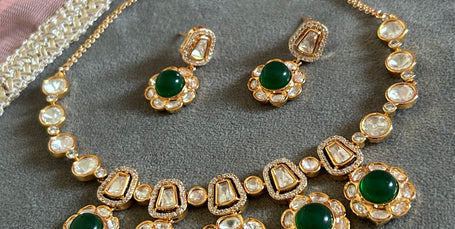 Ornate gold necklace with pearl and gemstone details on a gray surface.