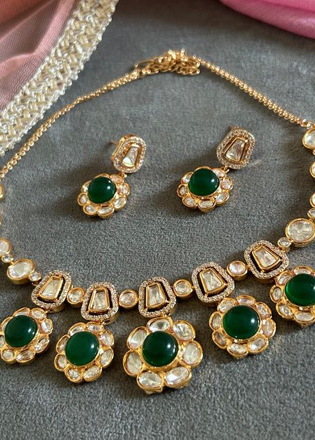 Ornate gold necklace with pearl and gemstone details on a gray surface.