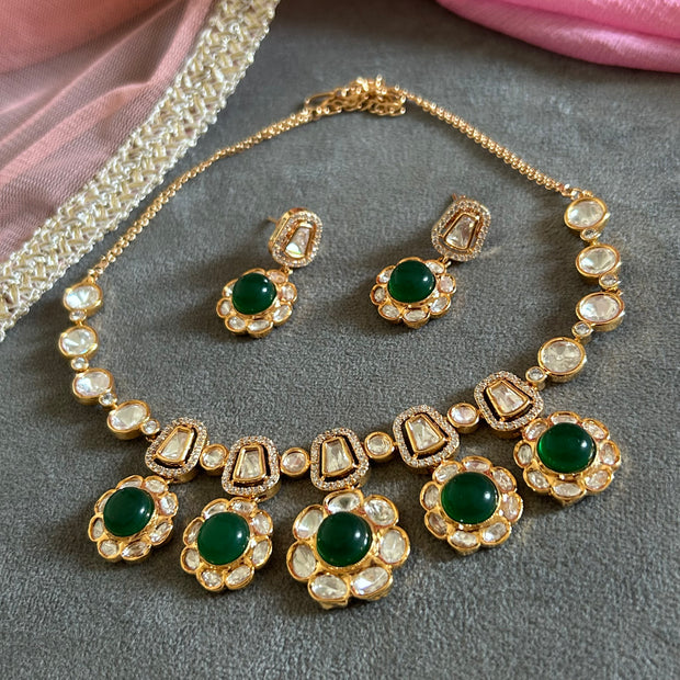 Ornate gold necklace with pearl and gemstone details on a gray surface.