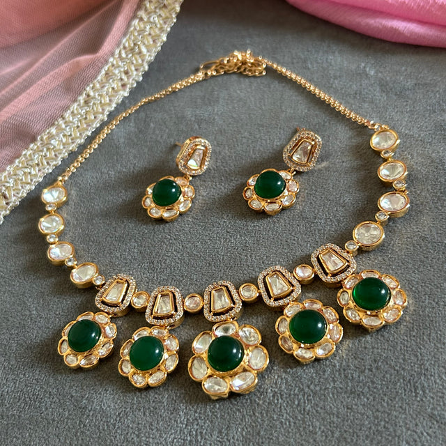 Ornate gold necklace with pearl and gemstone details on a gray surface.