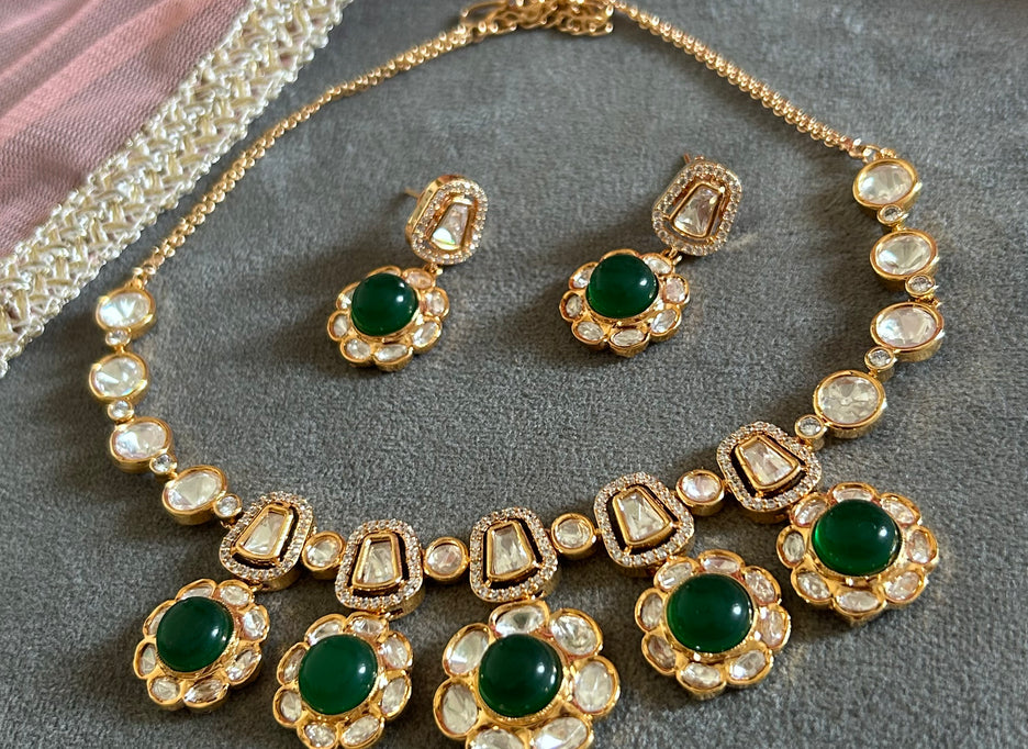 Ornate gold necklace with pearl and gemstone details on a gray surface.