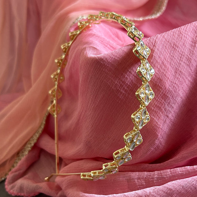 Gold headband with crystals on a pink fabric background