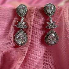 Pair of diamond earrings on a pink fabric background