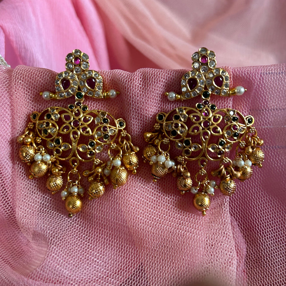 Gold earrings with pearls on a pink fabric background