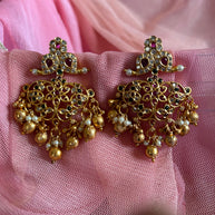 Gold earrings with pearls on a pink fabric background