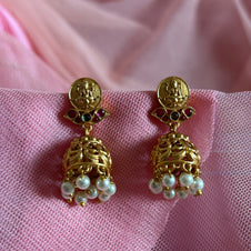 Gold earrings with pearl drops on a pink fabric background