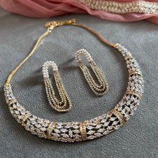 Jewelry set with necklace, earrings, and bracelet on a gray surface