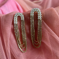 Pair of gold and pearl earrings on a pink fabric background